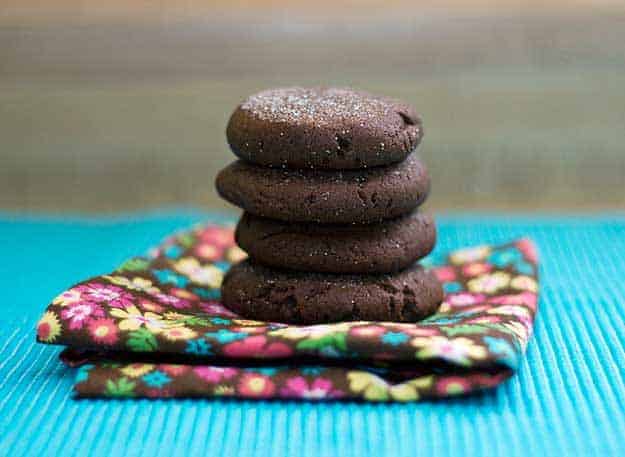 A stack of four chocolate cookies on a cloth napkin 