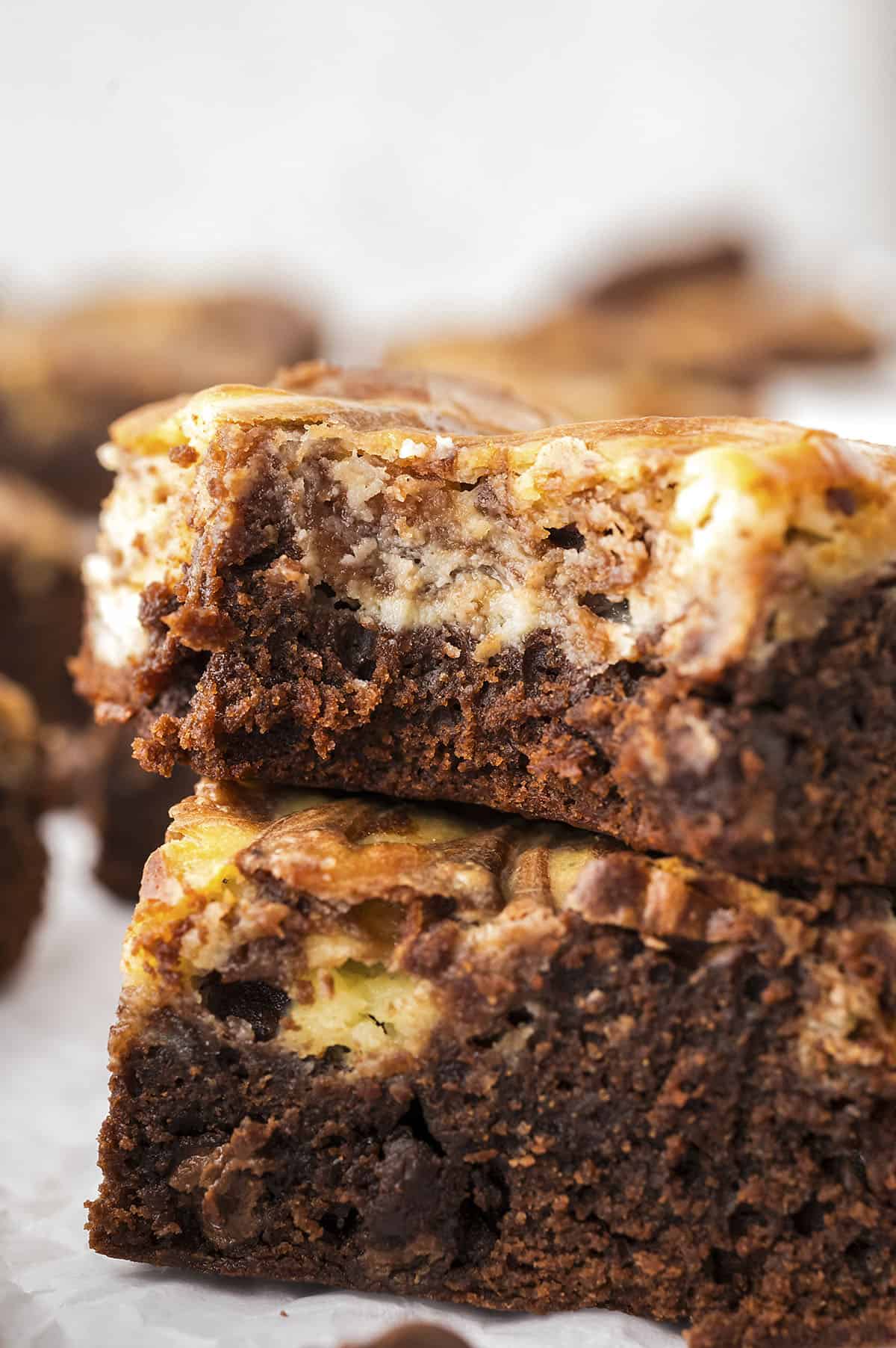 Brownies topped with cheesecake stacked togehter.
