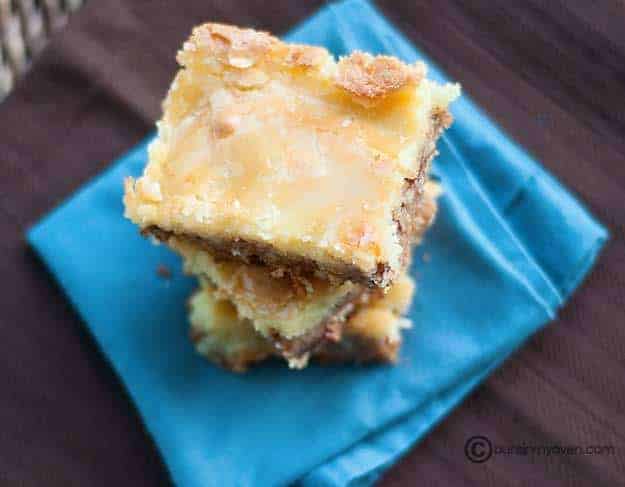 An overhead view of three stacked butter pecan squares on a cloth napkin 