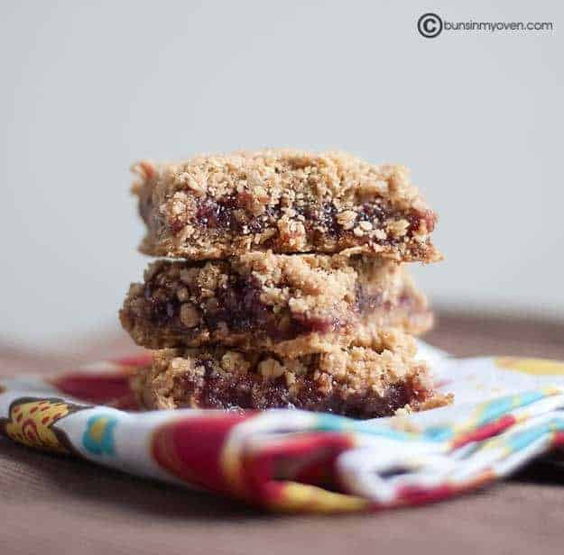 Three stacked raspberry oatmeal  bars on a folded cloth napkin