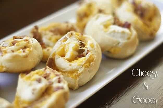 In the bacon and cheese pinwheels on a a long white plate 