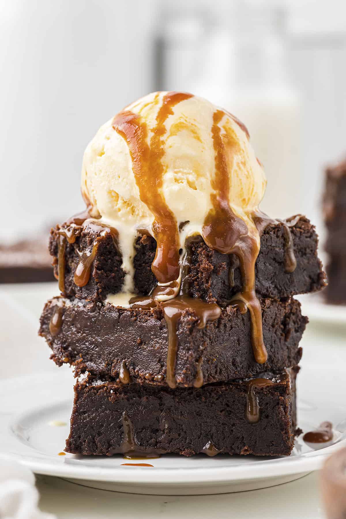 Stack of brownies topped with ice cream and caramel sauce.