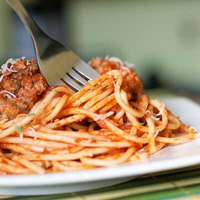 A closeup of a plate of spaghetti with a fork in it