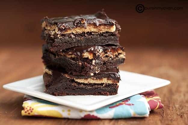 Stacked up buckeye brownies on a white plate.