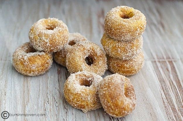 Stacked pumpkin donuts on a table.