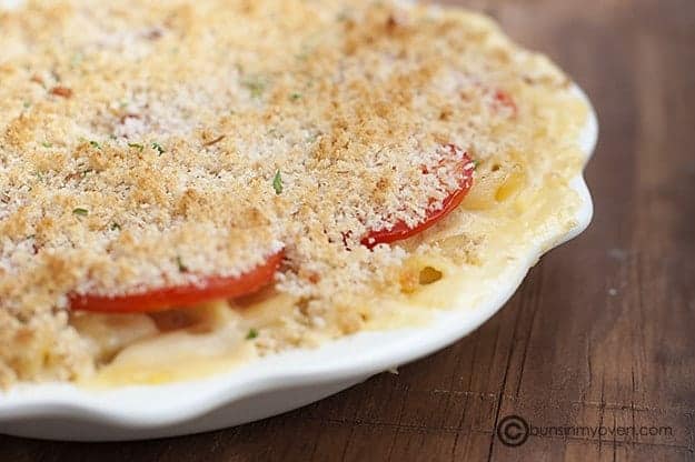 Creamy baked mac and cheese with tomatoes on white plate.
