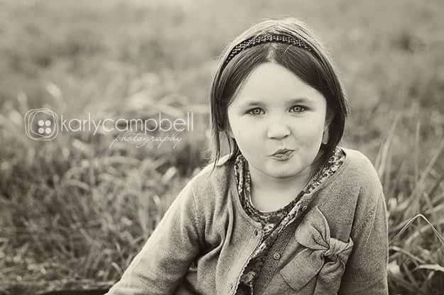 Black and white photo of a girl in sitting in the grass.