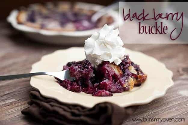 Blackberry cobbler on a white plate topped with whipped cream.