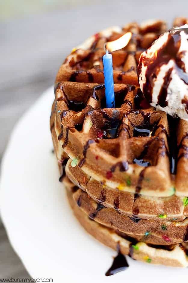 A closeup of a confetti waffle with a birthday candle in it 