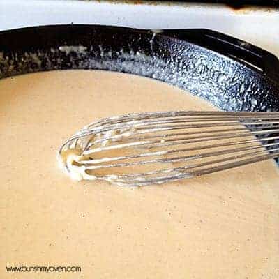 Alfredo sauce being whisked in a cast iron skillet 