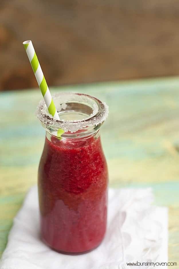 A milk jar full of raspberry lemonade with a straw in it 