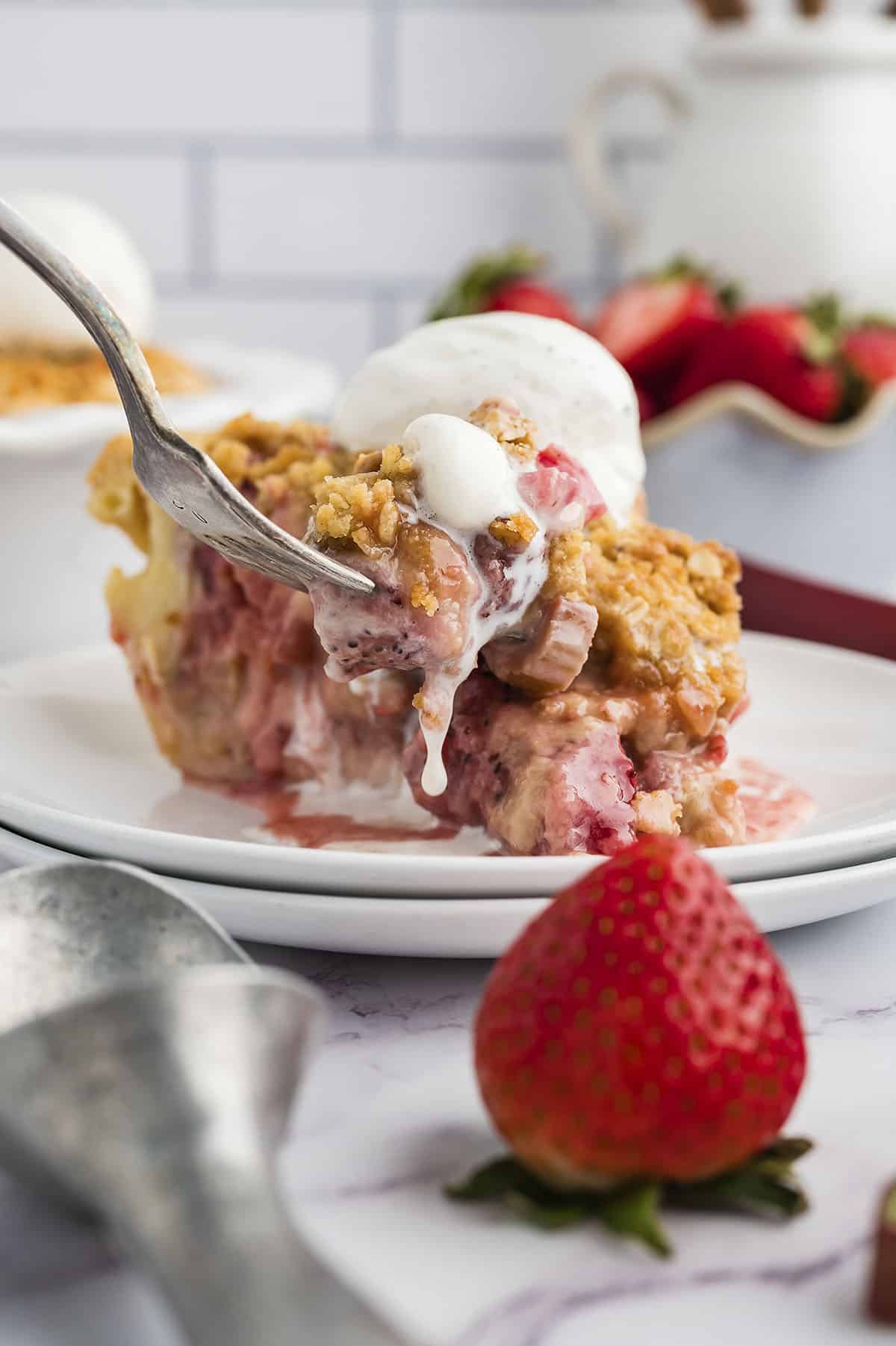 Strawberry rhubarb pie topped with a scoop of vanilla ice cream.