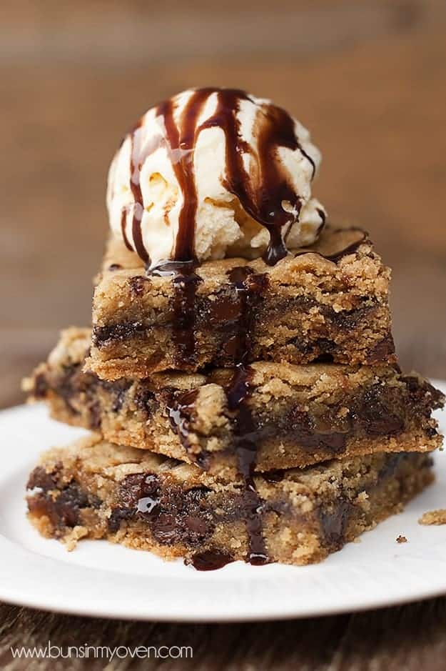 A closeup of three cookie bars with a scoop of ice cream on top 