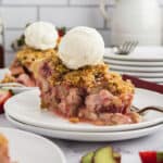 Slice of strawberry rhubarb pie on small white plate.