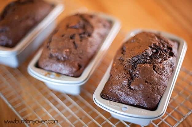 Three individual loaves of chocolate banana bread and separate bread pans 