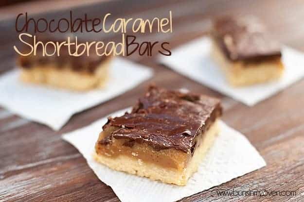 A close up of a few shortbread bars topped with caramel and chocolate on a table.