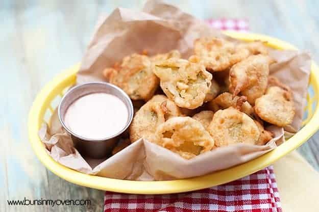 A close up of an appetizer basket with fried pickles and ranch dressing in it.