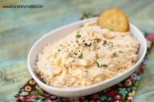 A bowl of pimento cheese dip with a ritz cracker in it.