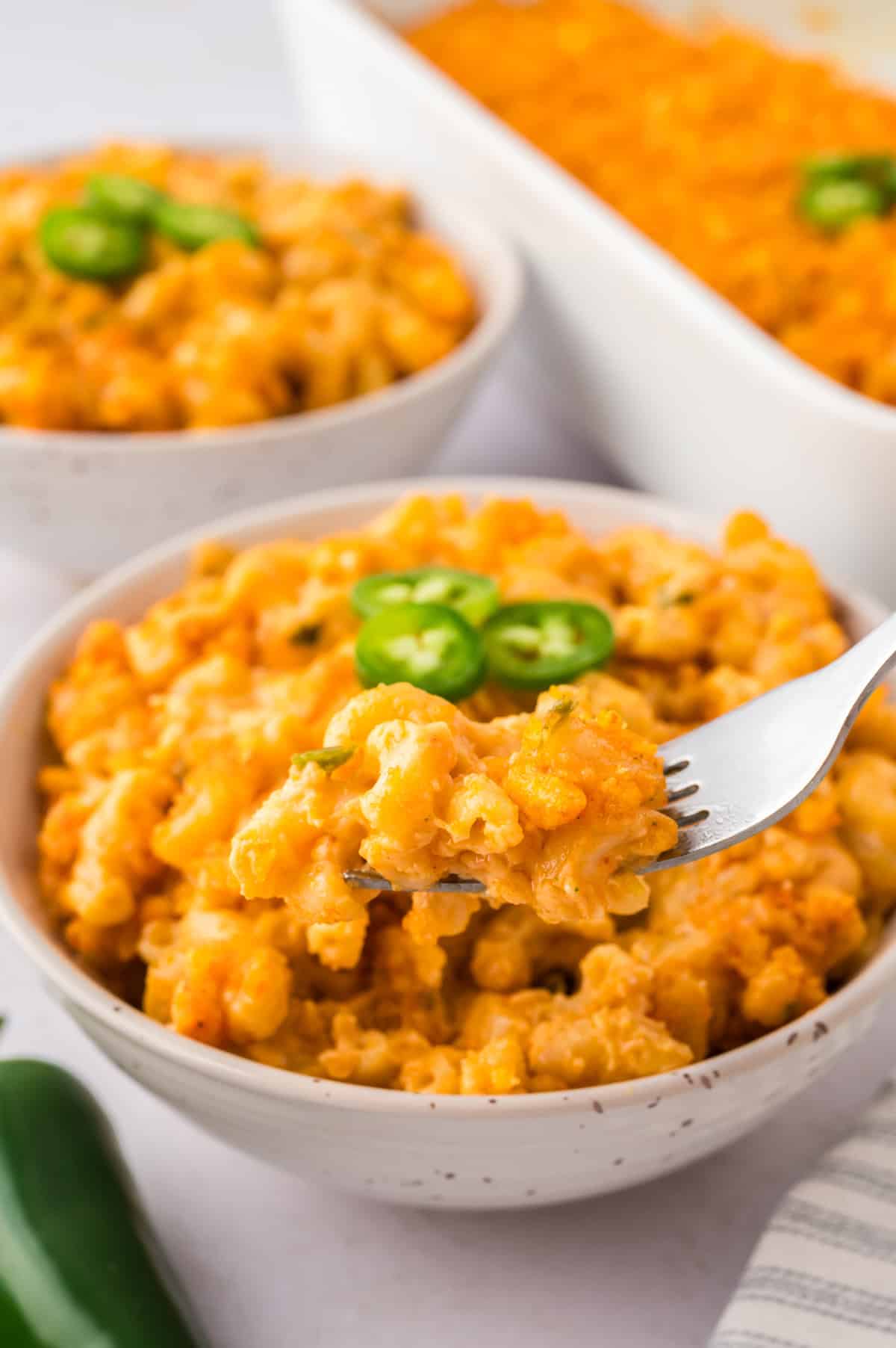 Forkful of jalapeno mac and cheese in bowl.