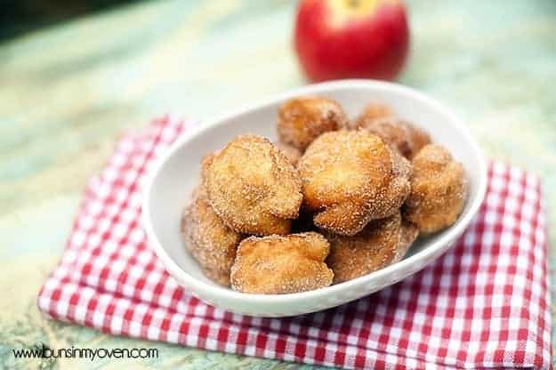 A close up of a bunch of apple fritters in an oval bowl.