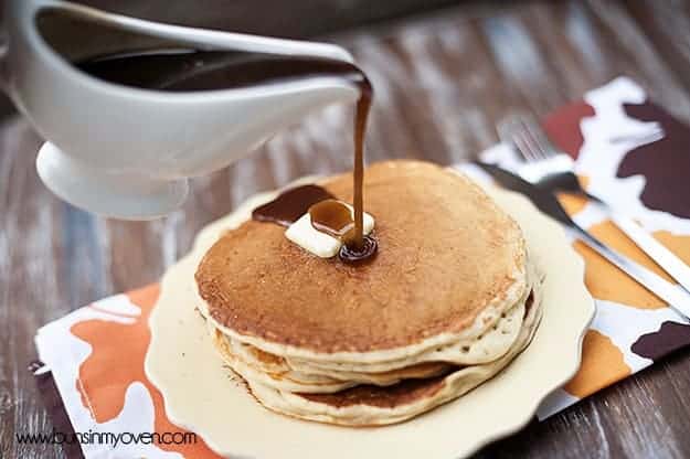 Cinnamon syrup being poured over a stack of pancakes