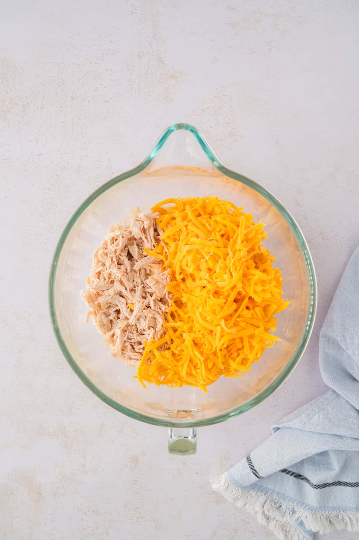 Cheese and chicken in mixing bowl.