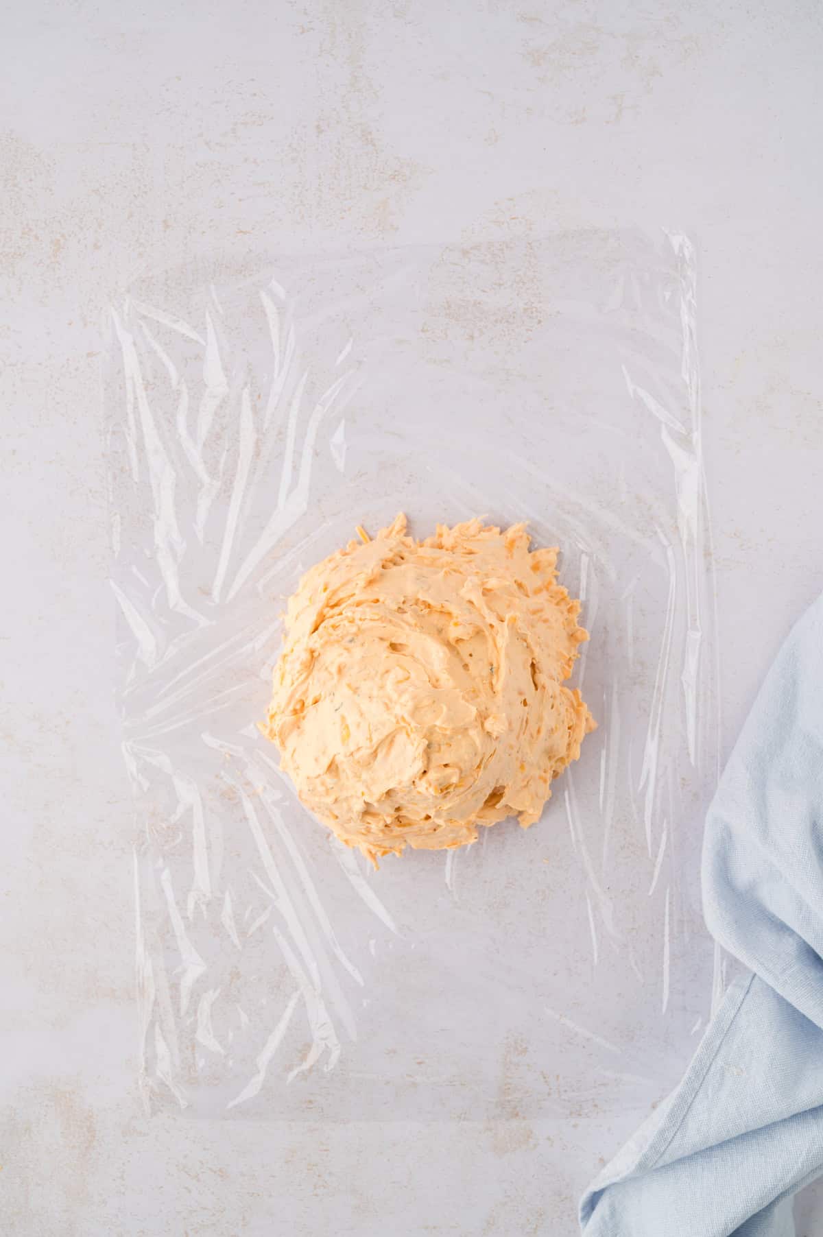 Buffalo chicken cheese ball on piece of plastic wap.