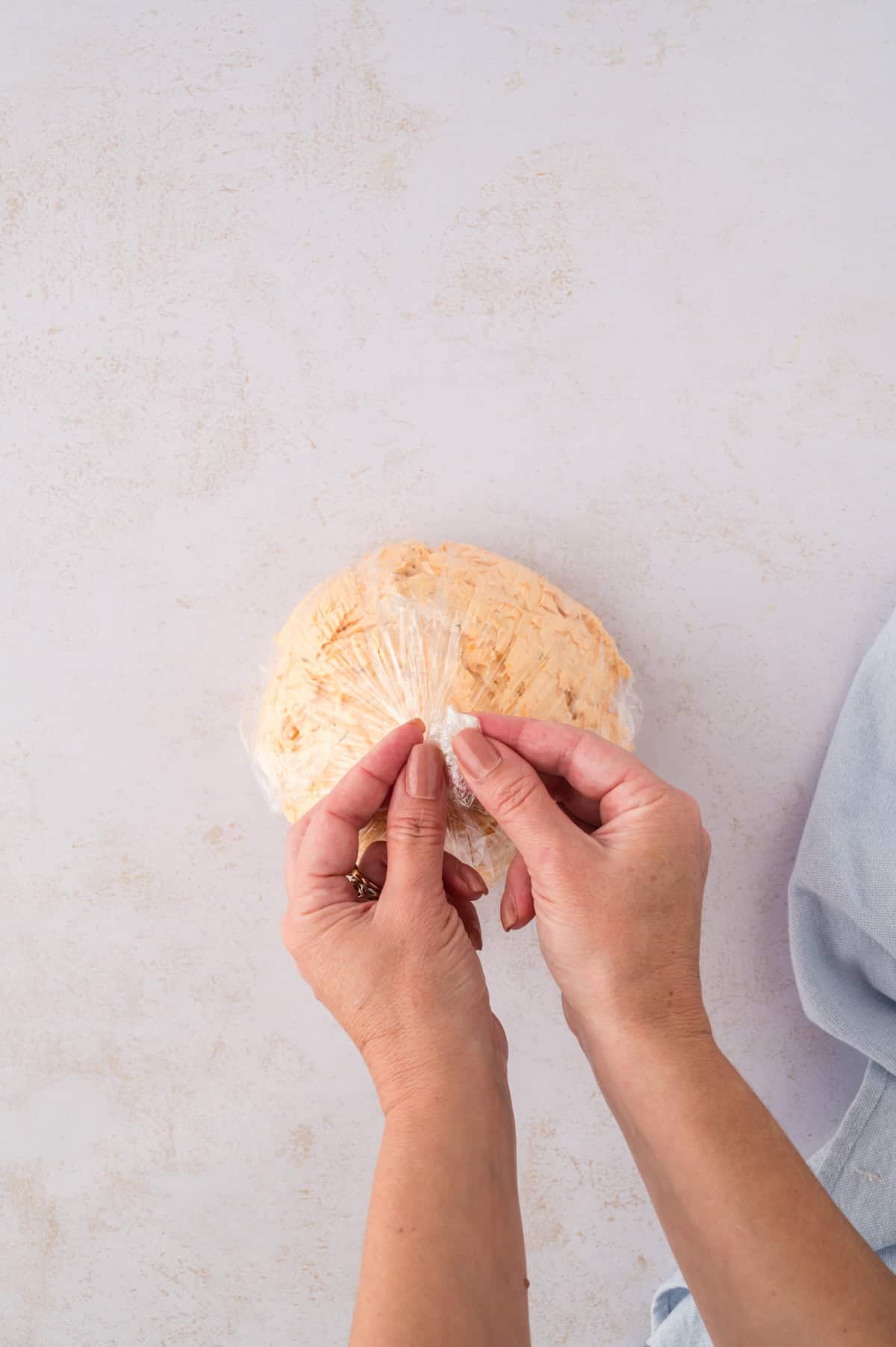 Cheese ball being wrapped in plastic.