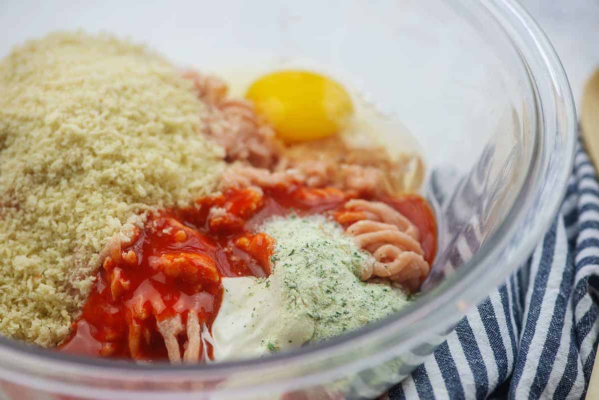 ingredients for chicken burgers in glass mixing bowl