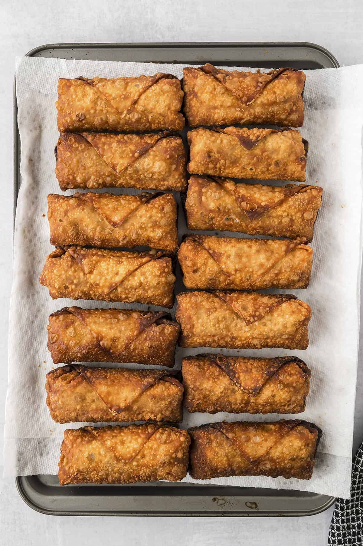 Pork egg rolls draining on sheet pan.