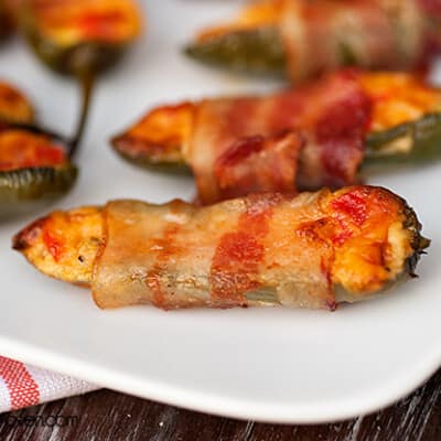 A close up of a bacon wrapped jalapeno pepper.