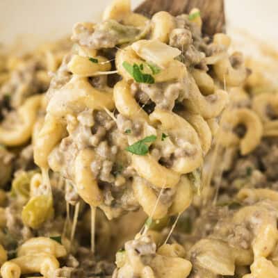 Philly cheesesteak pasta on wooden spoon in pan.