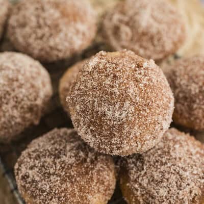 Applesauce donut muffins piled together on cooling rack.