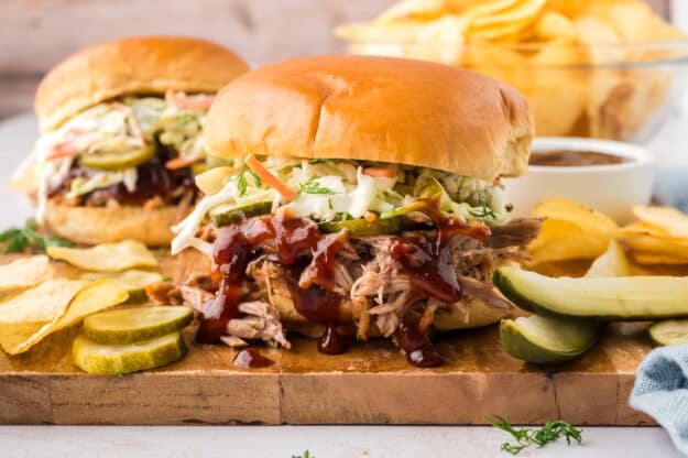 Slow cooker pulled pork made in the crock pot! Perfect for these easy sandwiches with dill pickle slaw and homemade barbecue sauce! This is one of our favorite recipes!