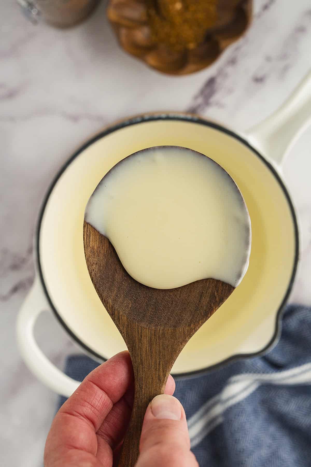 Melted white queso on wooden spoon.