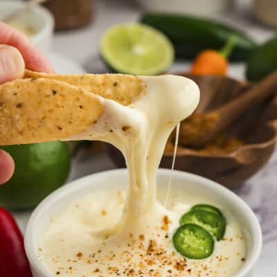 White queso dripping off of tortilla chip.