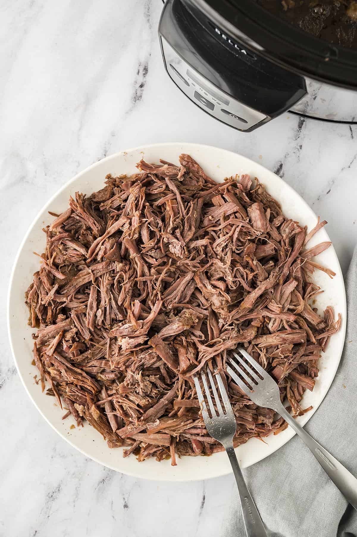 Shredded beef in white dish.