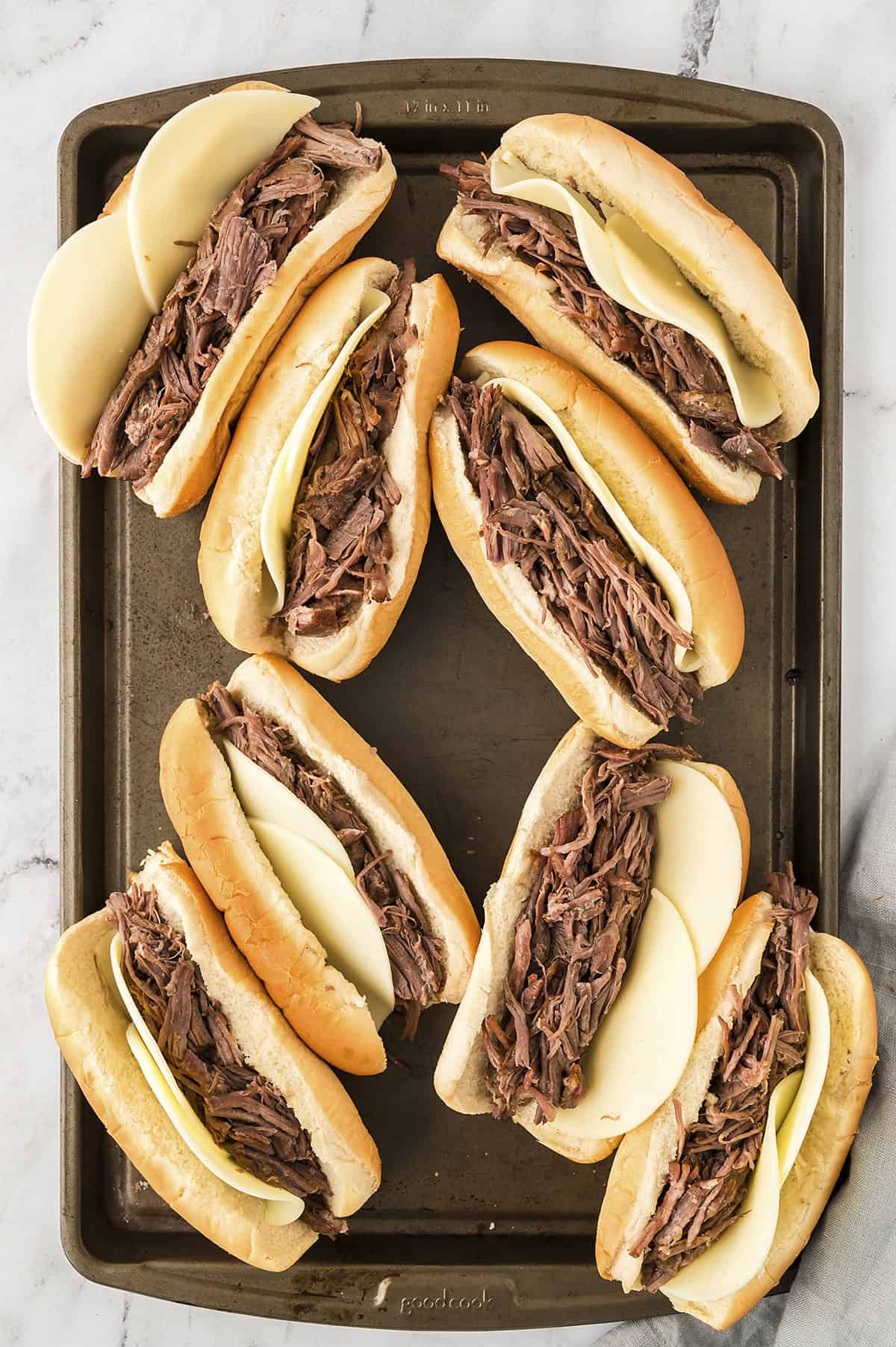 French dip sandwiches on baking sheet.