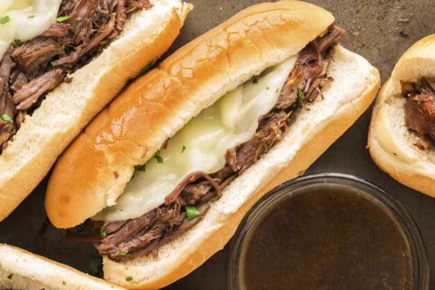 French dip sandwiches next to dish of au jus.