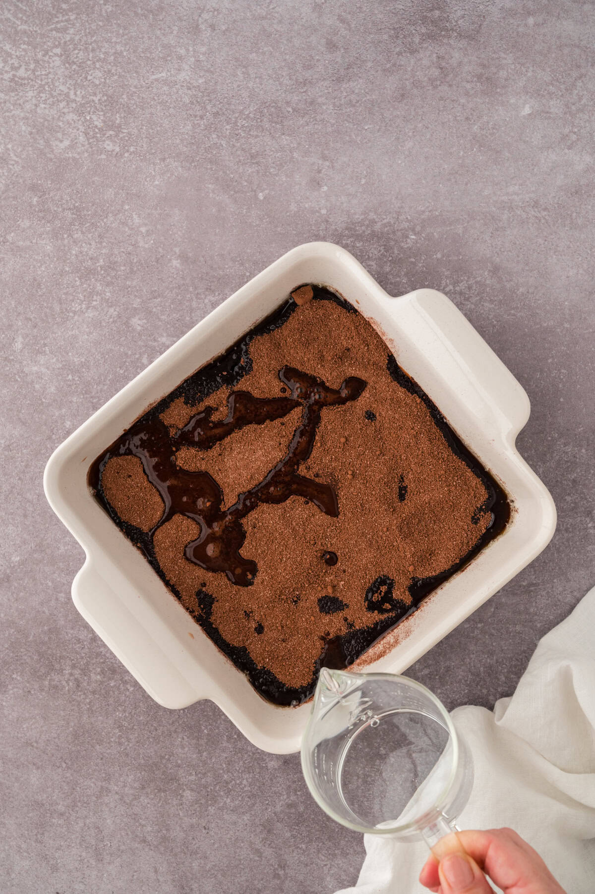 Hot water being drizzled over chocolate cobbler.