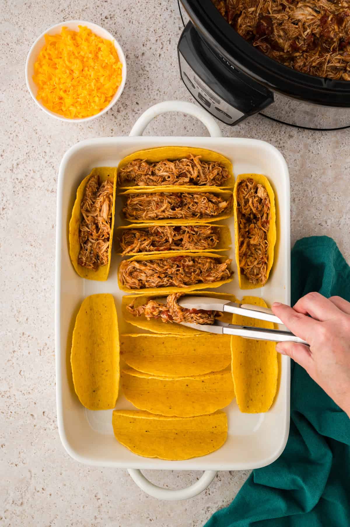 Shredded chicken being stuffed in taco shells.