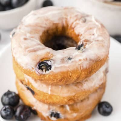 Stack of blueberry cake donuts on white plate.