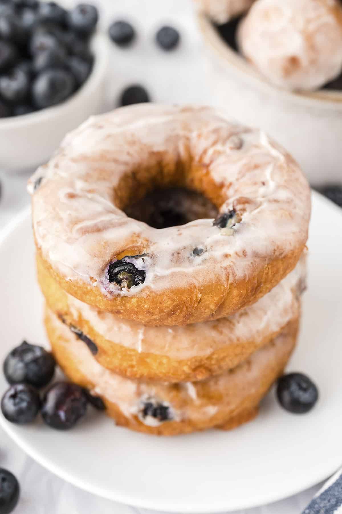 Stack of blueberry cake donuts on white plate.