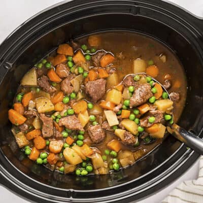 Slow cooker beef stew on ladle.