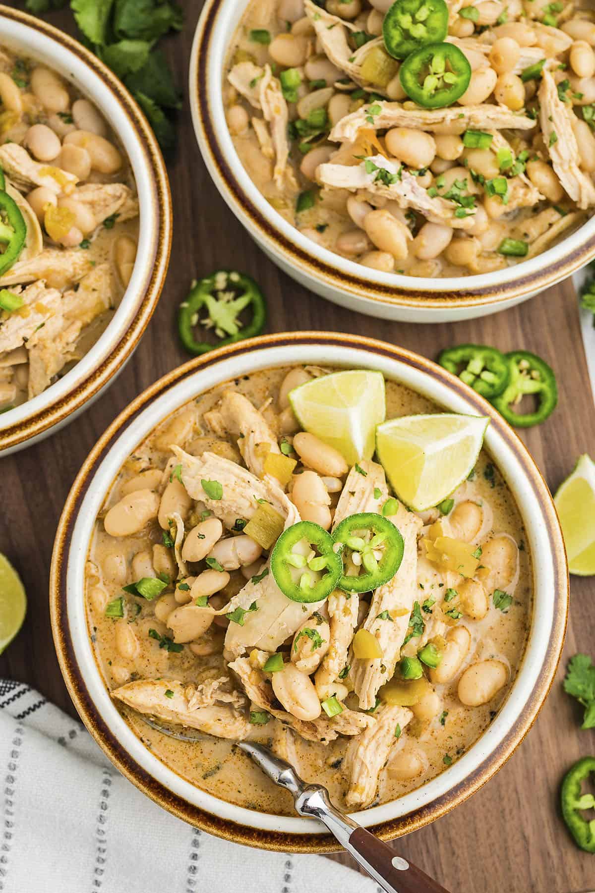 White chicken chili in bowls topped with jalapeno slices.