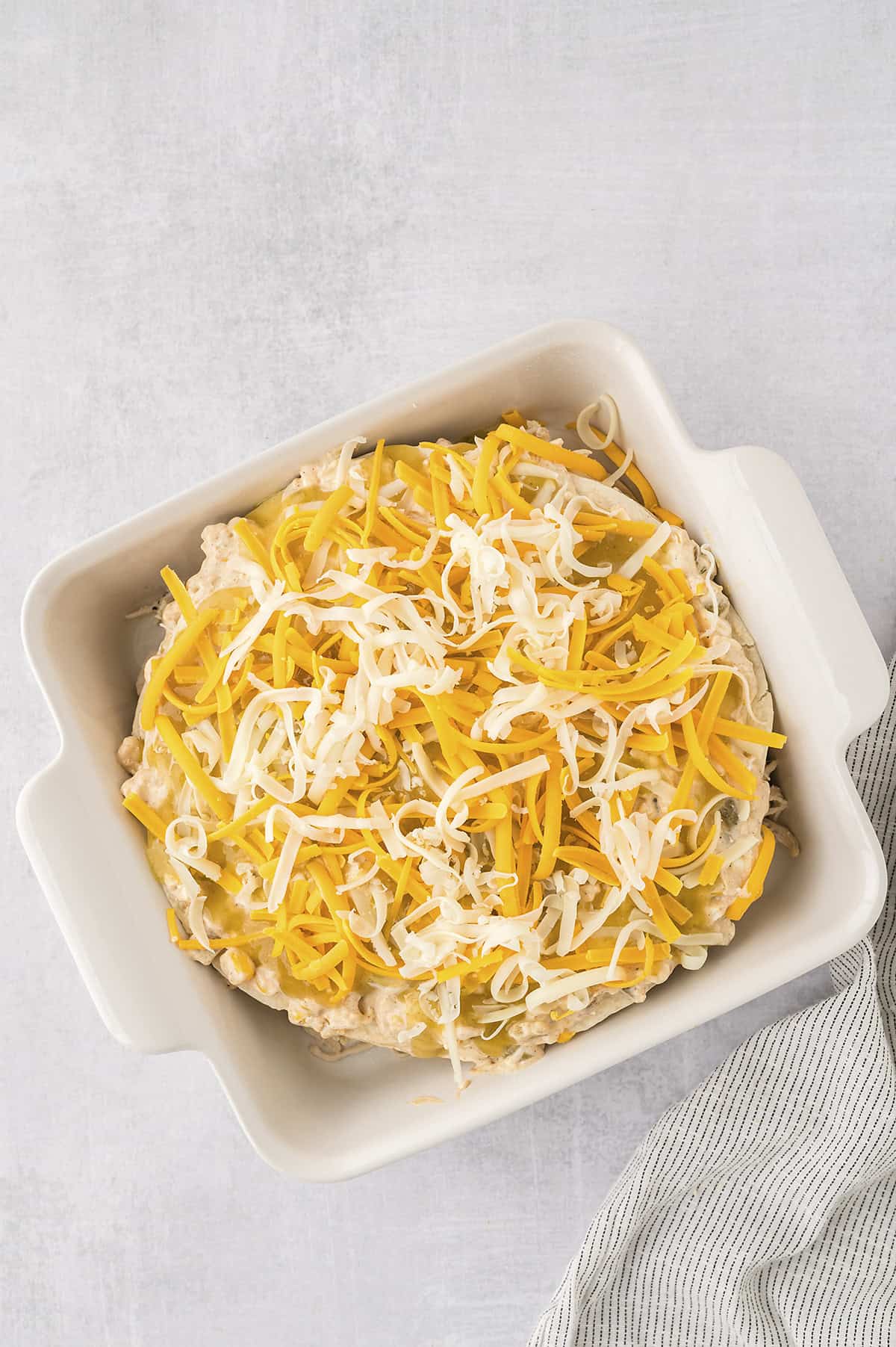 Chicken enchilada casserole topped with shredded cheese.