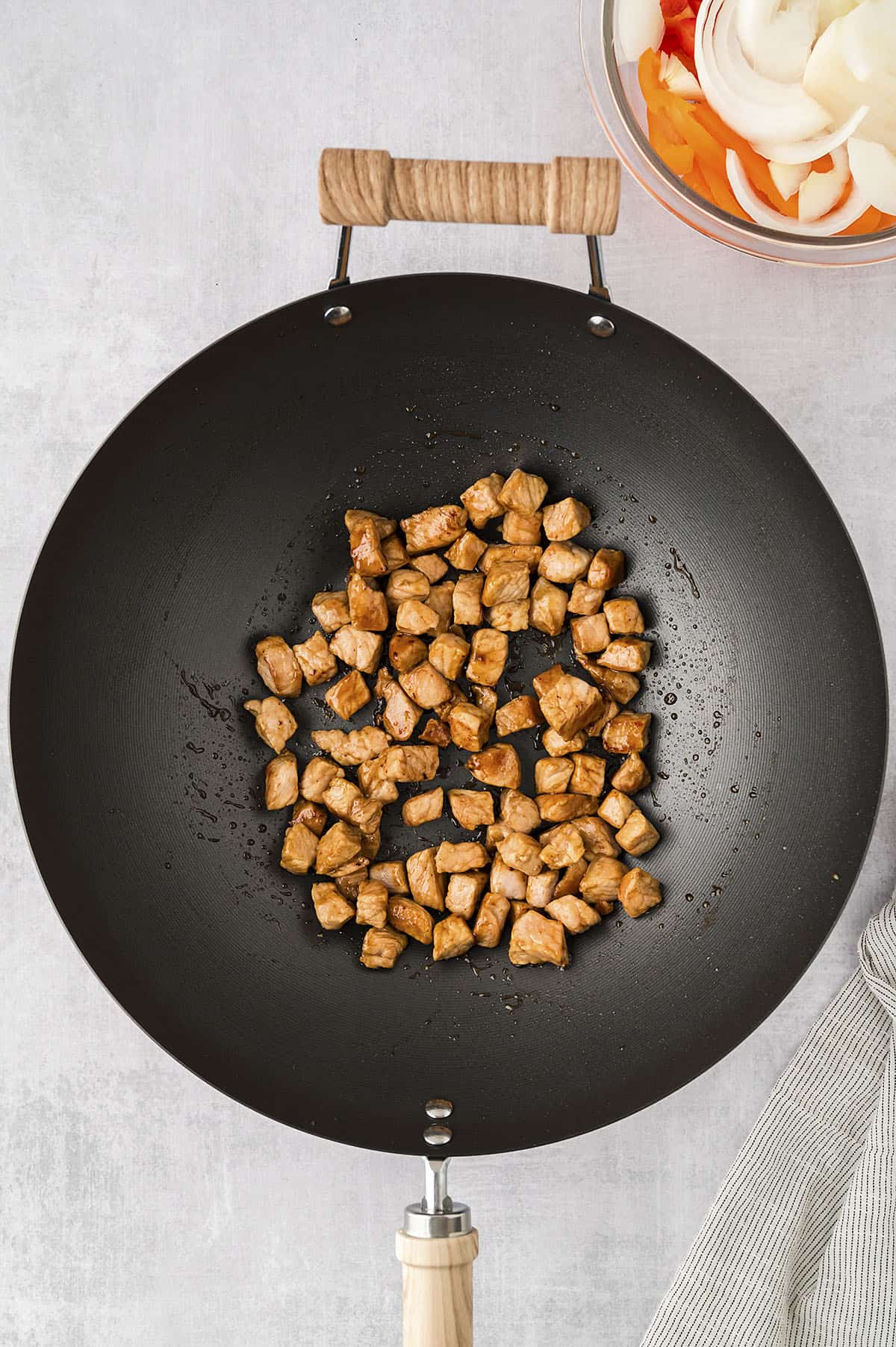 Diced pork chops being cooked in a wok.