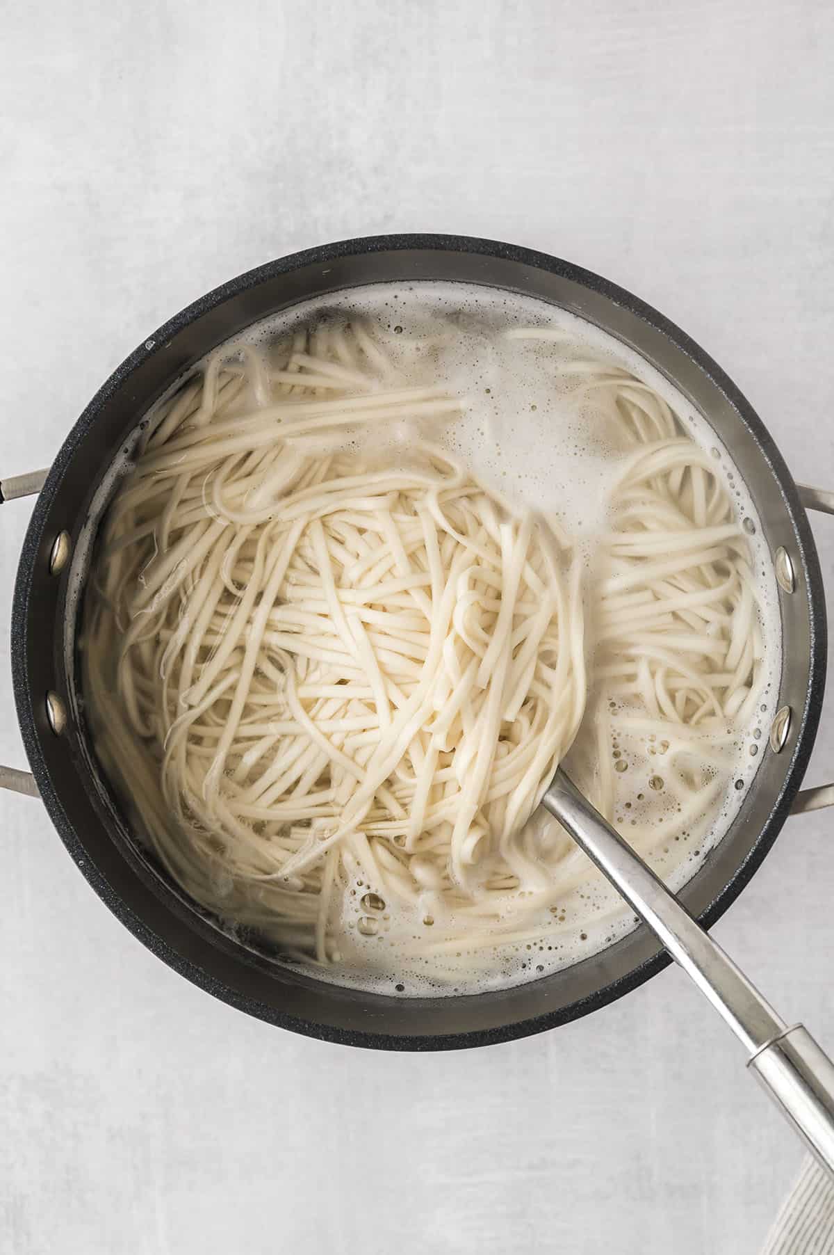 Lo mein noodles boiling in pot.