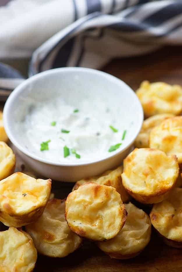 Sbuffi di patate accanto a un piatto di salsa bianca.