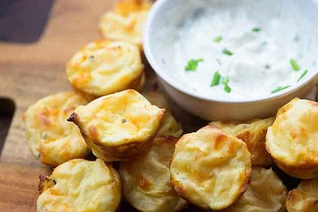 Bolitas de puré de patata apiladas junto a un plato de salsa.